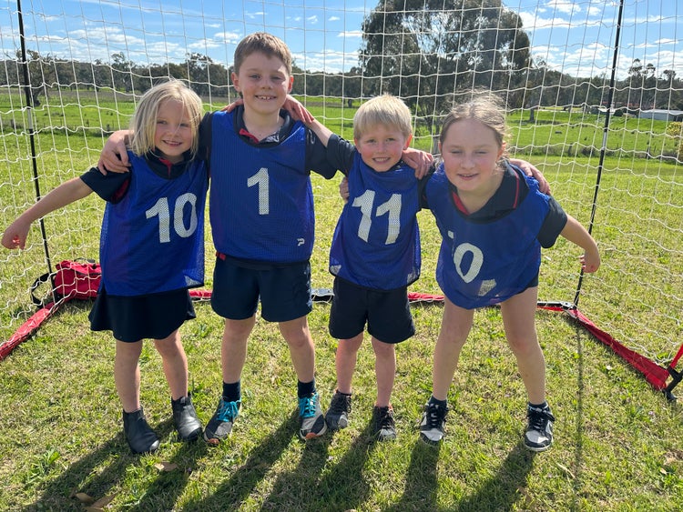 Four students arm in arm at soccer in the playground.