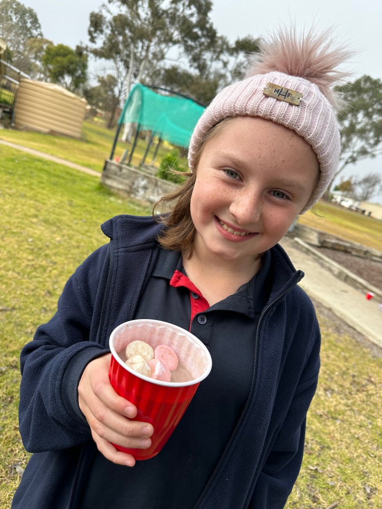 A student wearing a beanie drinking a hot chocolate.