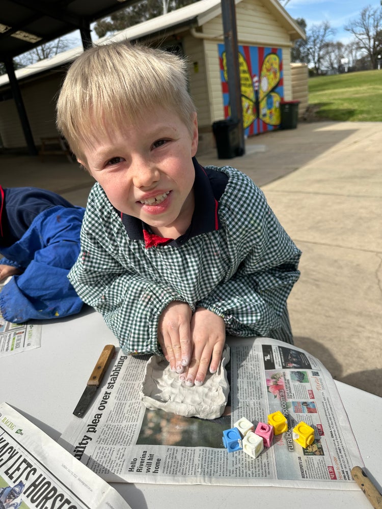 A student learning out in the playground, building a 3D container to measure objects in.