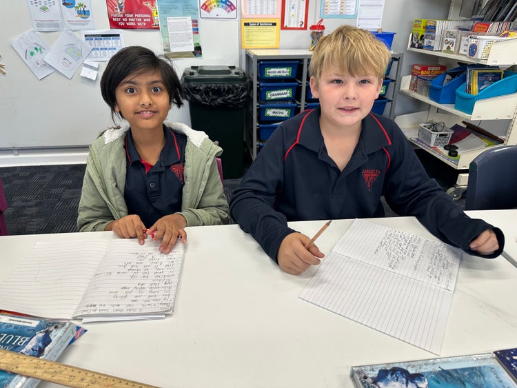 Two students completing a writing task in the classroom.