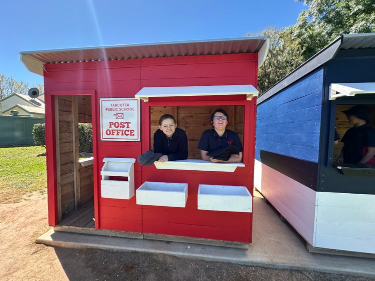 Two students playing inside our post office cubby house.